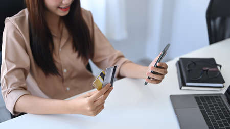 Smiling asian woman making baking online or payment online on her smart phone.