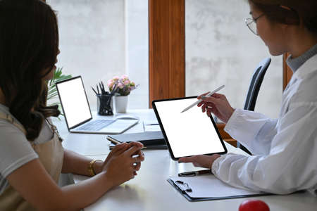 Female doctor holding digital tablet and explaining medical informations to her patient.の写真素材