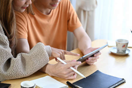 Young couple browsing internet with digital tablet together in living room.の写真素材