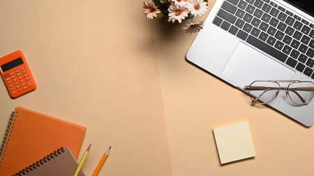 Above view laptop computer, notebook, glasses and calculator on beige background.の写真素材