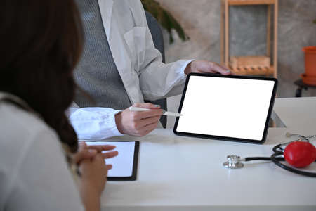 Cropped shot female doctor holding digital tablet and explaining medical informations to patient.