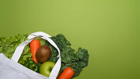 Eco bag with vegetables and fruits on green background.の写真素材