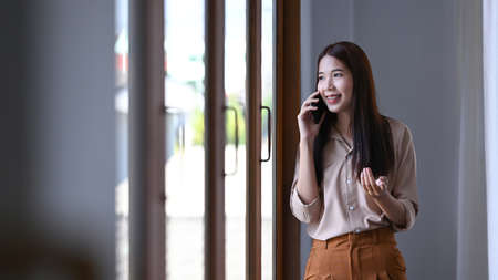 Successful businesswoman standing in office and talking on mobile phone.