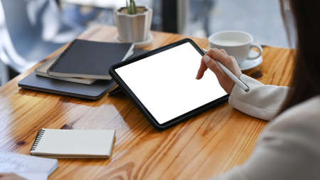 Over shoulder view of young businesswoman holding pen and using digital tablet.