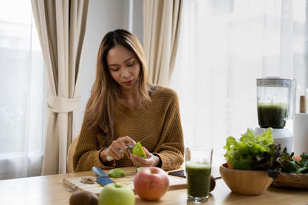 Healthy young woman holding glass with fresh green detox vegetable juice and smiling to camera.の写真素材