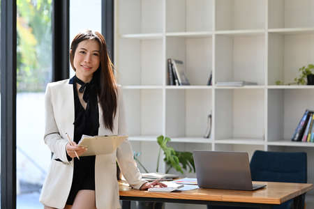 Confident young businesswoman standing in office and looking at  camera.の写真素材
