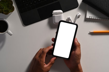 Above view young man hand holding smart phone on white table.