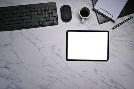 Modern workplace with digital tablet, notepad and coffee cup on marble table.の写真素材
