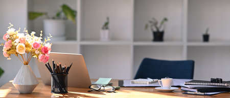 Comfortable workplace with laptop computer, flower pot, coffee cup and office supplies.の写真素材