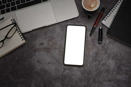 Mockup smart phone, laptop computer, notebook and coffee cup on dark stone textured table.