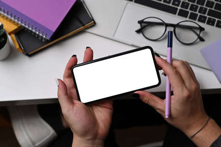 Overhead shot businesswoman holding pen and using smart phone.の写真素材