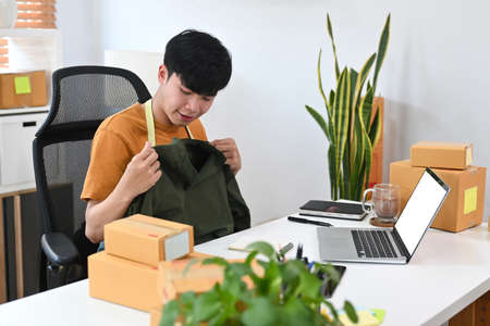 Smiling asian man confirming orders from customer on mobile phone.の写真素材