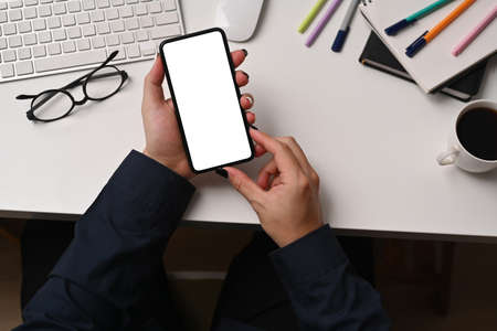 Overhead shot businesswoman holding pen and using smart phone.