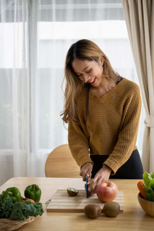Smiling young asian woman preparing vegetarian meal in the kitchen.の写真素材