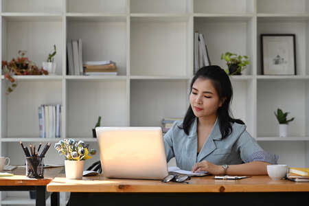 Asian business woman using laptop computer at office desk.の写真素材