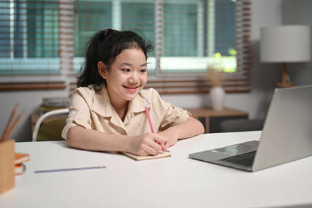Cheerful asian girl holding book and smiling at camera.