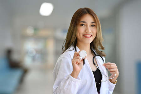 Portrait of beautiful female doctor white uniform holding stethoscope and smiling at camera.