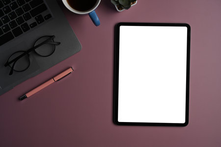 Digital tablet, stylus pen, laptop computer and coffee cup on purple background.