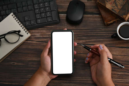 Mockup image of woman holding smart phone with blank screen on wooden table.の写真素材