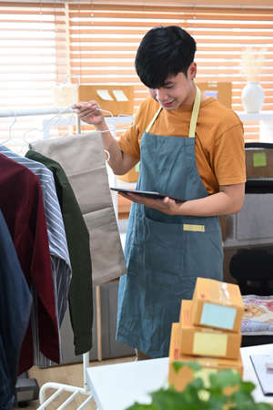 Asian man taking photo of shoes with smart phone for upload to website online shop.の写真素材