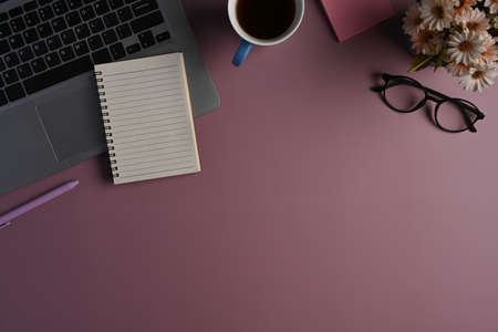 Stylish workplace with laptop computer, glasses, sticky note and notebook on purple background.の写真素材