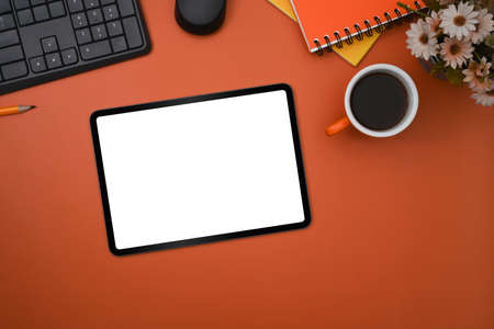 Flat lay, mockup digital tablet, coffee cup and notebook on orange background.