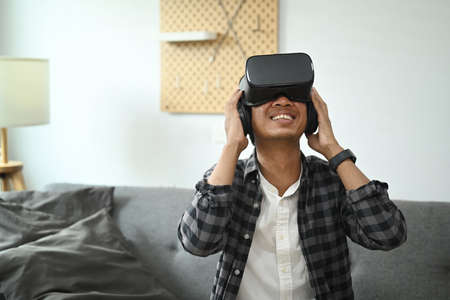 Young man playing video games with virtual reality headset  in living room.の写真素材