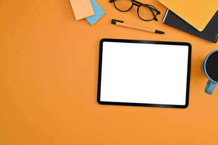 Mockup digital tablet, glasses, coffee cup and notebooks on yellow background. Flat lay.の写真素材