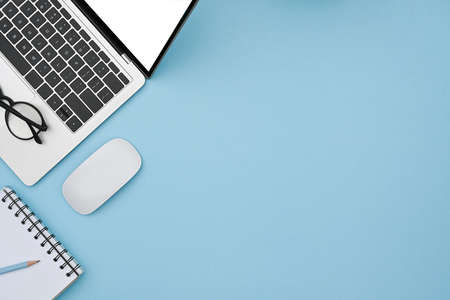 Mock up laptop computer, wireless mouse and notebook on blue background.の写真素材