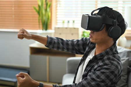 Excited man experiencing virtual reality while using virtual reality headset for entertaining.