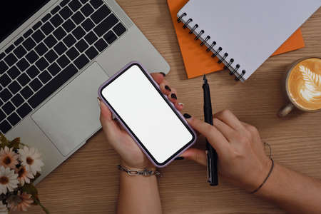 Woman holding pen and mockup mobile phone with white empty screen.