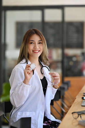 Attractive asian female doctor standing with arms crossed and smiling to camera.