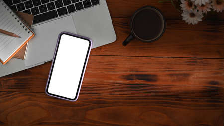 Smart phone, notepad, coffee cup and flower pot on wooden table, Top view.