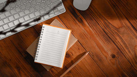 Top view empty notepad, pencil and wireless keyboard on wooden table. Flat lay.