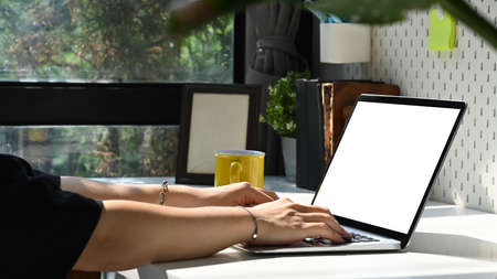 Close up view young woman holding book and using computer laptop on white table.
