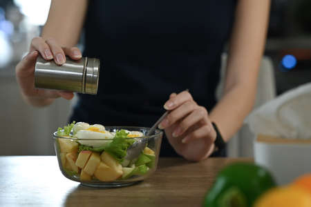 Young woman cutting fruits on a wooden board while making healthy breakfast in home kitchen.