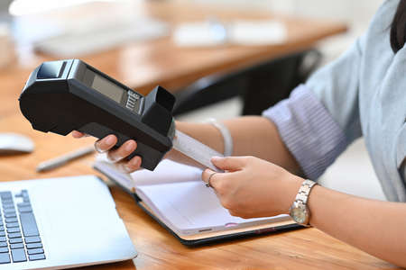 Young female customer swiping a debit card through payment terminal.の写真素材