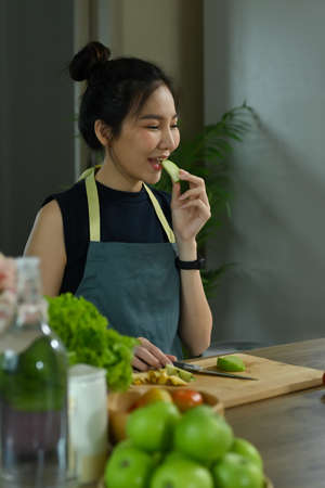 Vegetarian woman reading recipe on digital tablet while making green vegetables smoothie in home kitchen.の写真素材