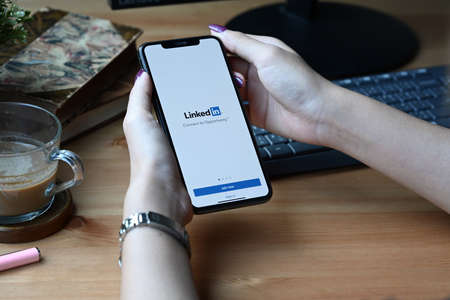 Chiang Mai, Thailand - Mar 01,2022: Woman holding smart phone with LinkedIn app. LinkedIn is a social network for the business community.のeditorial素材