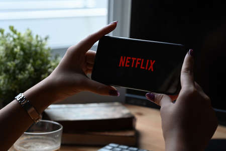 Chiang Mai, Thailand - Mar 01,2022: Woman holding iPhone 11 Pro Max with Netflix logo on screen. Netflix is a global provider of streaming movies and TV series.のeditorial素材