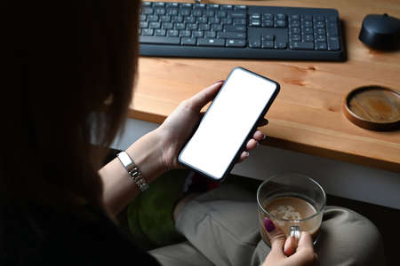 Over shoulder creative woman using smart phone at workplace.