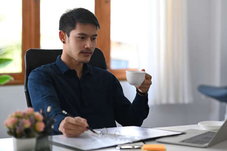 Confident asian man entrepreneur working with computer at modern workplace.