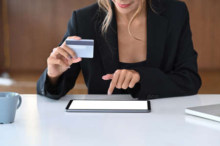 Young stylish woman holding debit card and making payment online or shopping online on digital...
