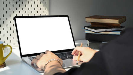 Mockup laptop computer with empty display, coffee cup and books on white table. Home office...