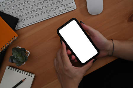 Close up view woman sitting at office desk with computer laptop and using mobile phone.
