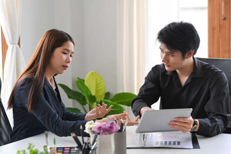 Two creative people sharing ideas and discussing about color design at creative office.