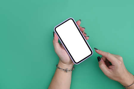 Mockup image of woman holding smart phone with blank screen on green background.