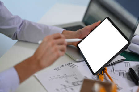 Close up view male engineer using digital tablet while working on architectural project at office.の写真素材