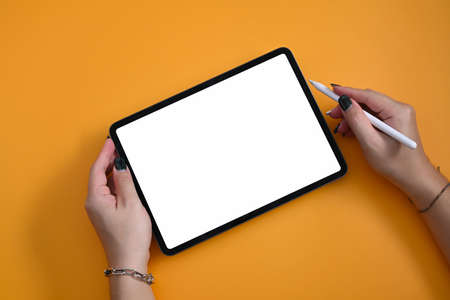 Above view woman holding mockup digital tablet and stylus pen on yellow background.の写真素材