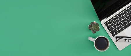 Computer laptop, coffee cup and succulent plant on green background with copy space for text. Flay lay.の写真素材